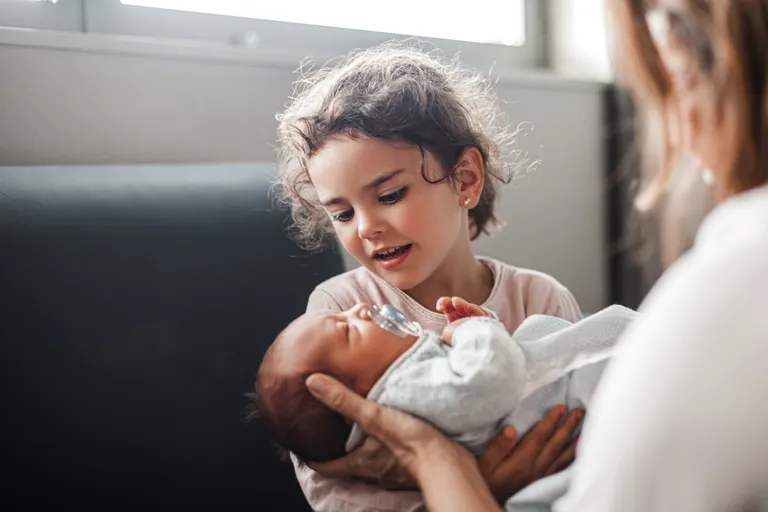 Young girl holding a newborn baby