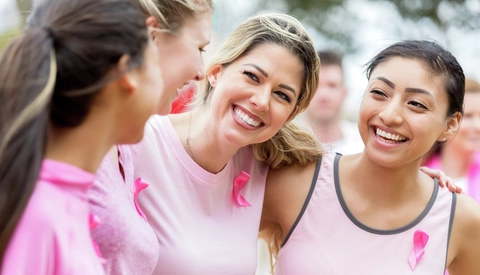 Community members wearing pink ribbons at a breast cancer awareness event.