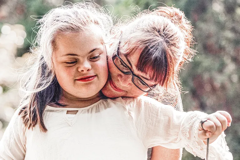 Young girl with Down syndrome hugging her mom