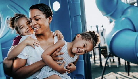 Happy mother holding her little daughters at a BlueCross Healthy Place