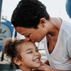 Mother kisses young daughter on forehead at a BlueCross Healthy Place