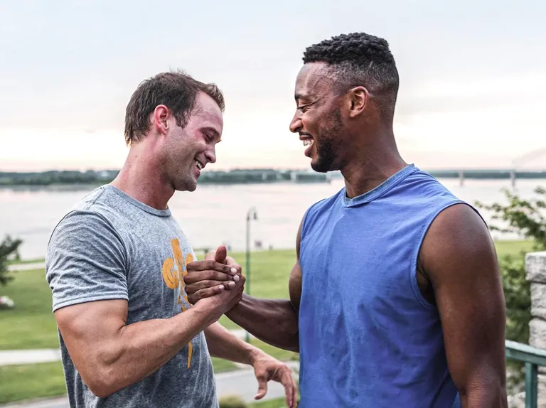 Two men grip hands in unity after outdoor workout