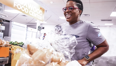 A BlueCross BlueShield of Tennessee Team Blue volunteer transporting groceries at a food center