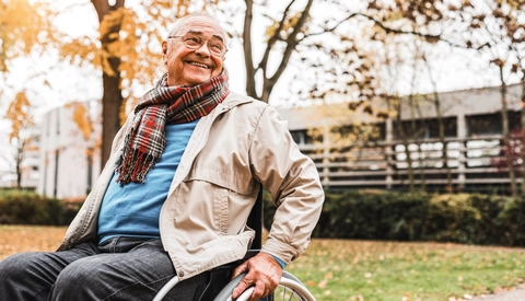 Smiling senior man in wheelchair outdoors