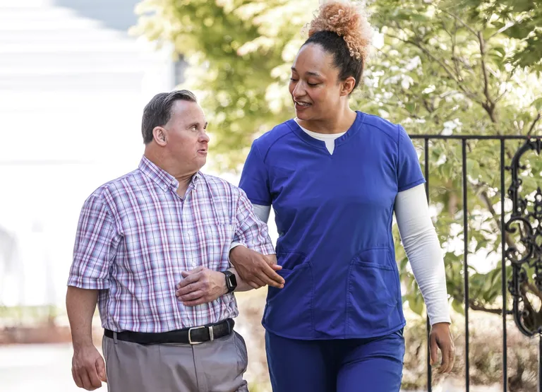 Happy portrait of a caregiver walking with a man with down syndrome