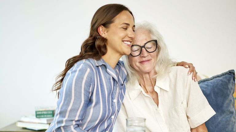 Happy senior woman being cared for by friendly caregiver at home.