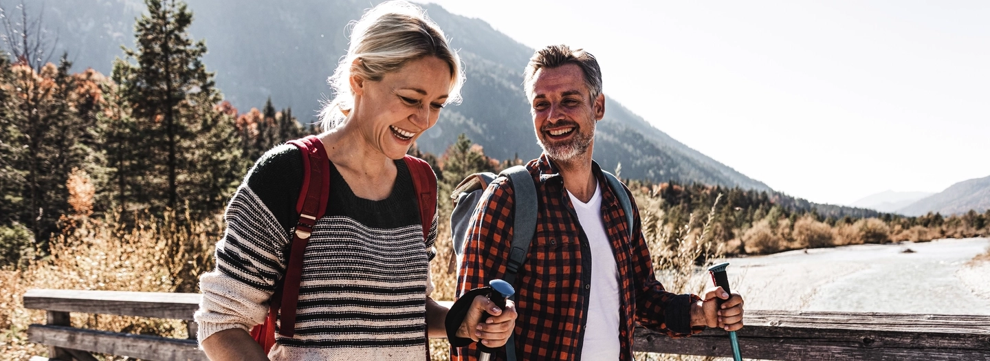 Happy couple on a hiking trip crossing a bridge