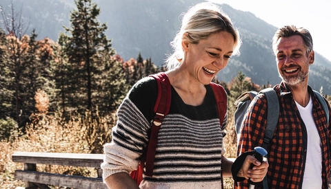 Happy couple on a hiking trip crossing a bridge