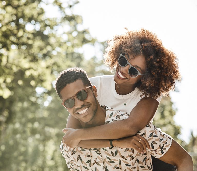 Young couple enjoying piggyback ride on sunny day