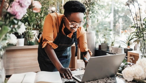 Person working in plant shop with laptop