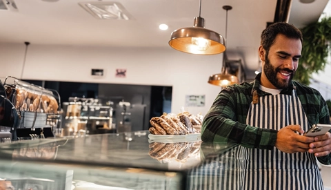 Man working at a cafe and using his cell phone