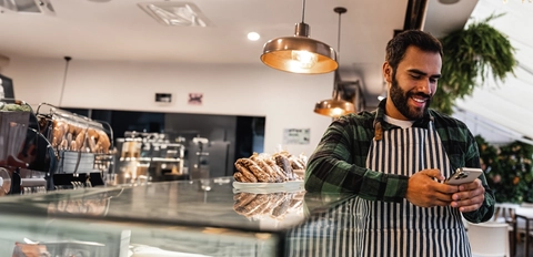Man working at a cafe and using his cell phone