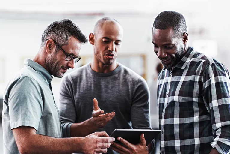 Three coworkers having a discussion over a digital tablet