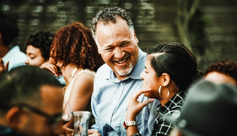 Laughing uncle in discussion with niece during outdoor family dinner party