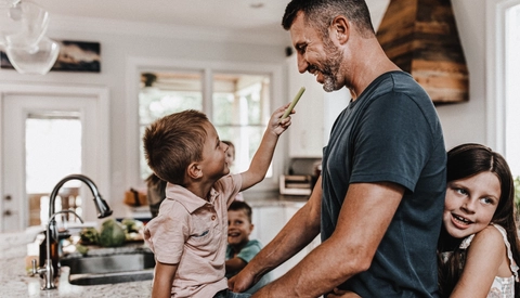 Father at home in kitchen with children