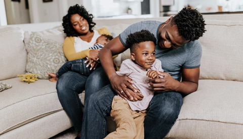Young cheerful parents having fun with their small kids at home