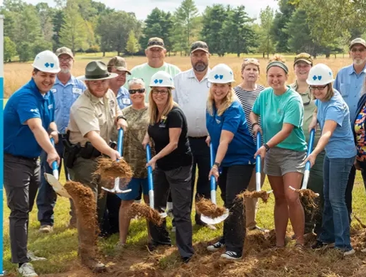 Community members take part in an outdoor groundbreaking event with shovels beside a sign promoting active and healthy places in Tennessee.