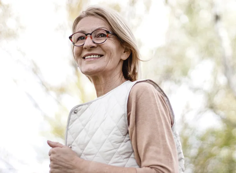 Mature blond woman with glasses walks in the park