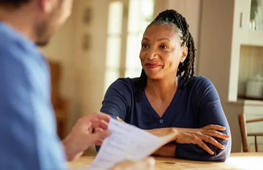 Two people discussing documents together at a table in a residential home