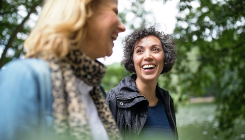 Happy mature woman looking at friend in forest