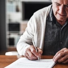 Senior man sitting alone in his home and signing his will