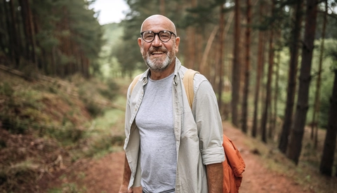 Senior man hiking on mountain with use of hiking pole