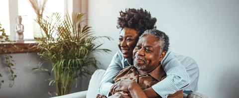 Senior man and his middle aged daughter smiling at each other embracing