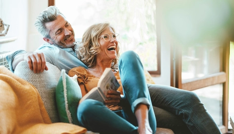 Cheerful mature couple sitting on sofa at home