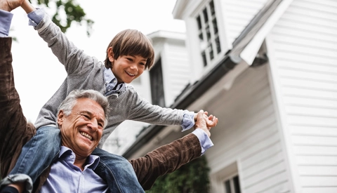 Man carrying grandson on shoulders outdoors