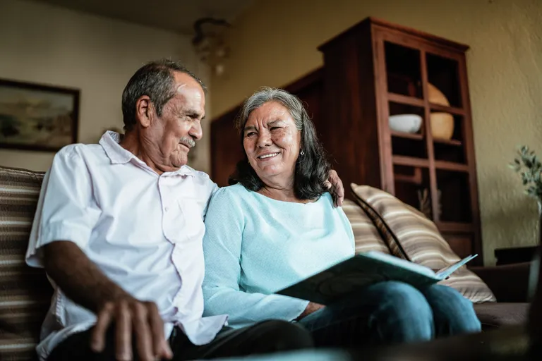 Senior couple looking a photo album sitting on sofa in the living room