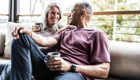Senior couple having coffee and embracing on back porch of vacation home