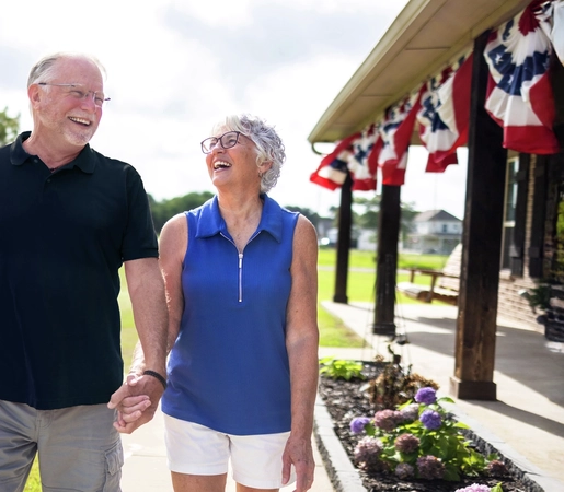 Man and woman holding hands and laughing on their front lawn