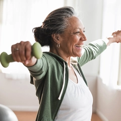 Older Hispanic woman lifting weights in living room