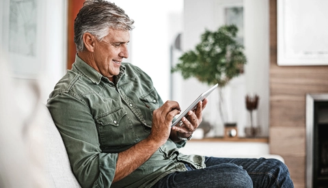 Mature man using a digital tablet at home