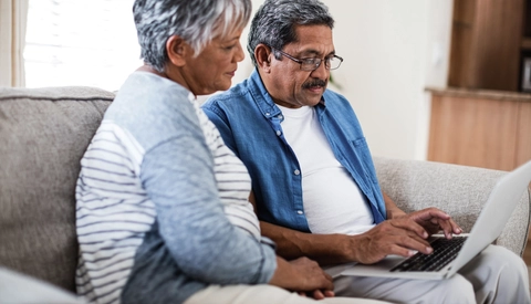 Senior couple using laptop in living room