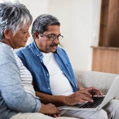 Senior couple using laptop in living room