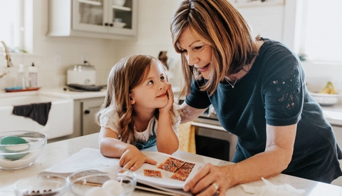Grandma and little granddaughter look at cookbook in kitchen�
