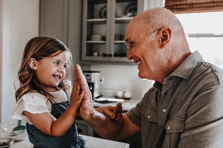 Grandfather and granddaughter hi-fiving in kitchen