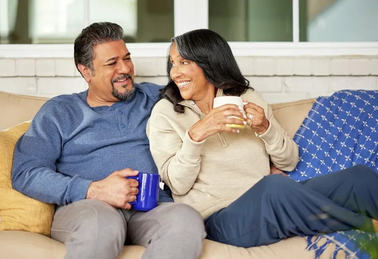 Retirement couple drinking tea on porch at home, relax and chatting conversation together on porch.