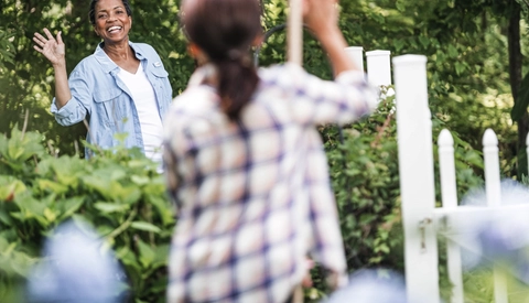 Friendly Neighbors Greeting Across a White Picket Fence on a Sunny Day