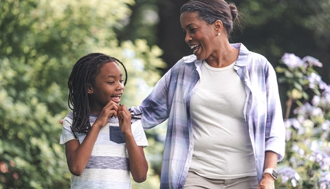 Smiling grandmother and granddaughter walking in garden