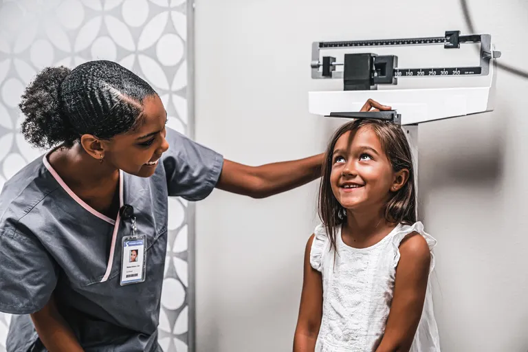 Nurse measuring height of girl