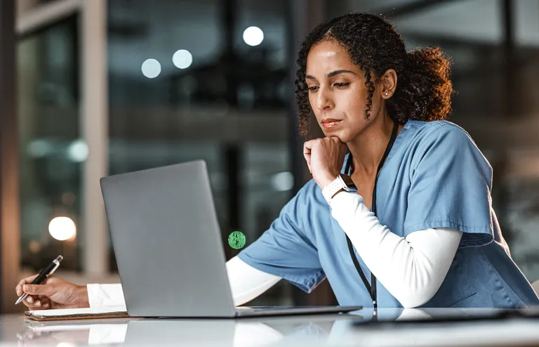 Doctor in deep thought while reviewing data on laptop