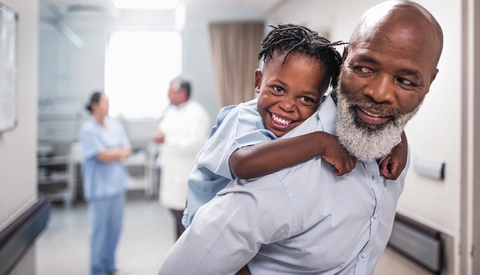 Young Child Holds Onto Dad's Shoulders in Medical Setting