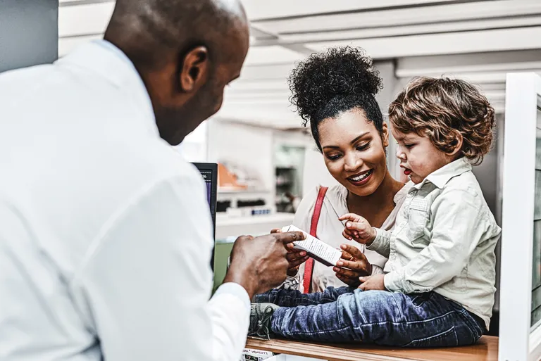 Child Sitting on Pharmacy Counter While Pharmacist and Mother Talk
