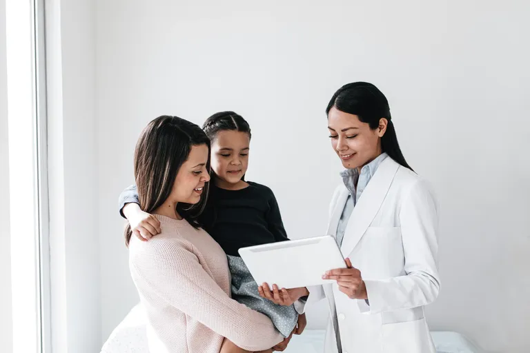 Female Doctor Showing Mother A Document