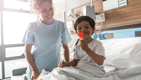 Female Medical Provider Smiles As Young Patient Enjoys Lollipop