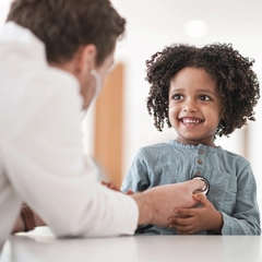 Child Smiling While Doctor Conducts Check-Up