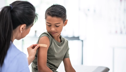Provider applying a bandaid to a young member's arm in the office.