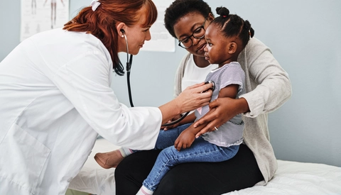 Pediatrician examining a little girl during a consultation with her mother